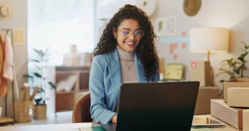A woman on her laptop next to shipping boxes