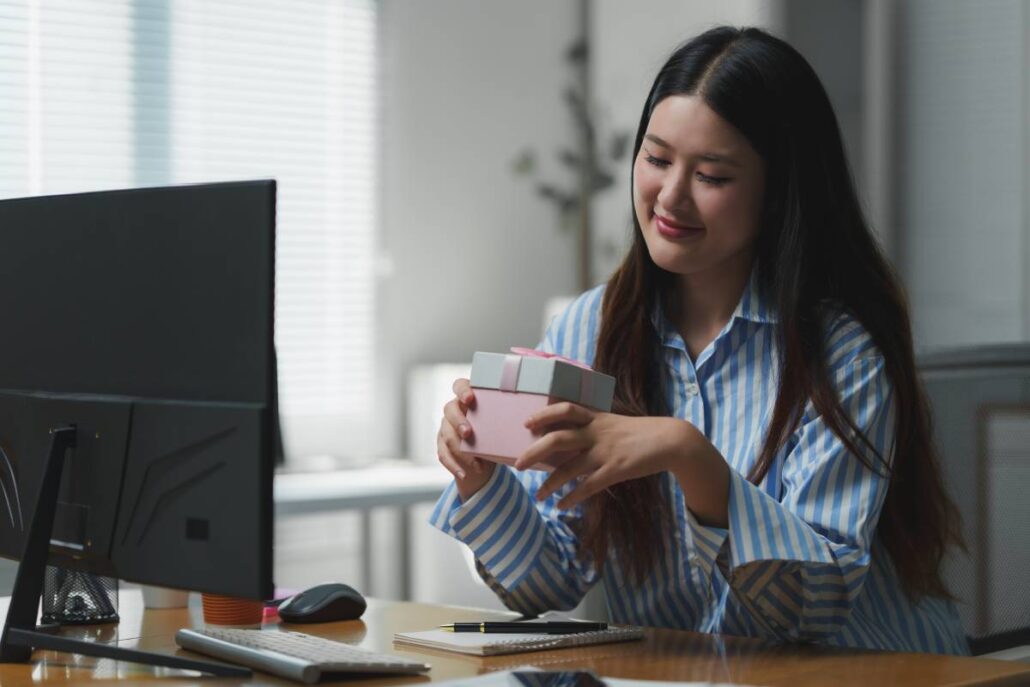 A worker at her desk looking at a gift