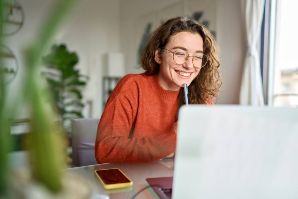 A smiling woman looking at her laptop