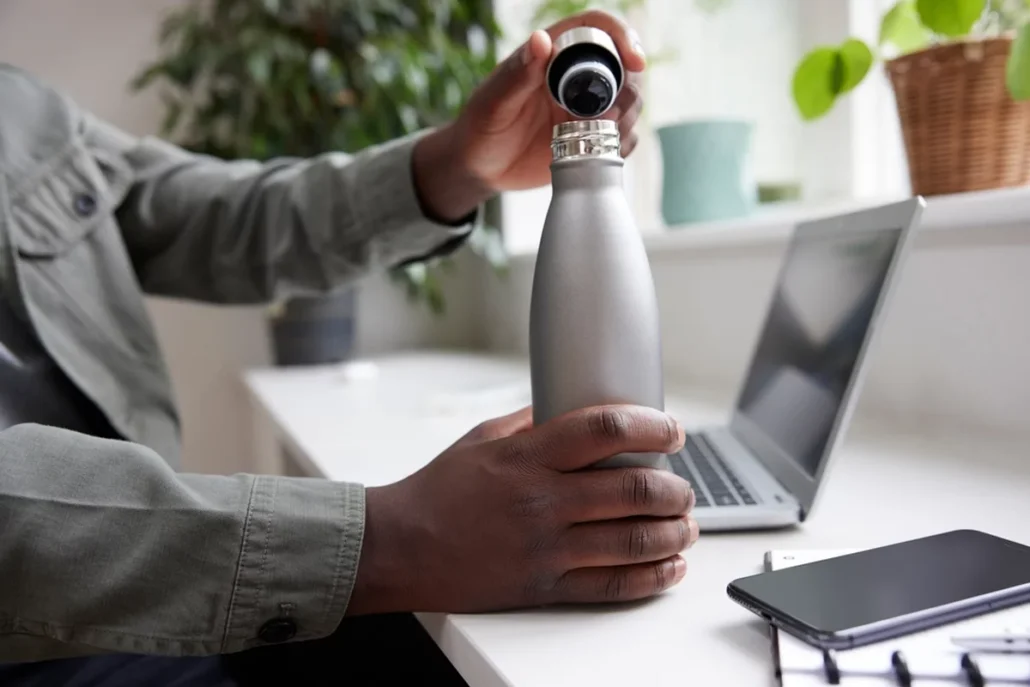 A man using a reusable water bottle at work