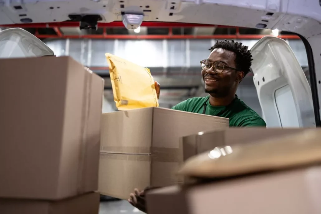 A worker loading packages into the back of a van.